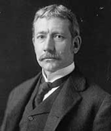 A man with a large mustache and a early-twentieth century suit