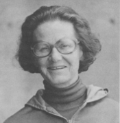 A woman with short dark hair, glasses, and wearing a turtleneck