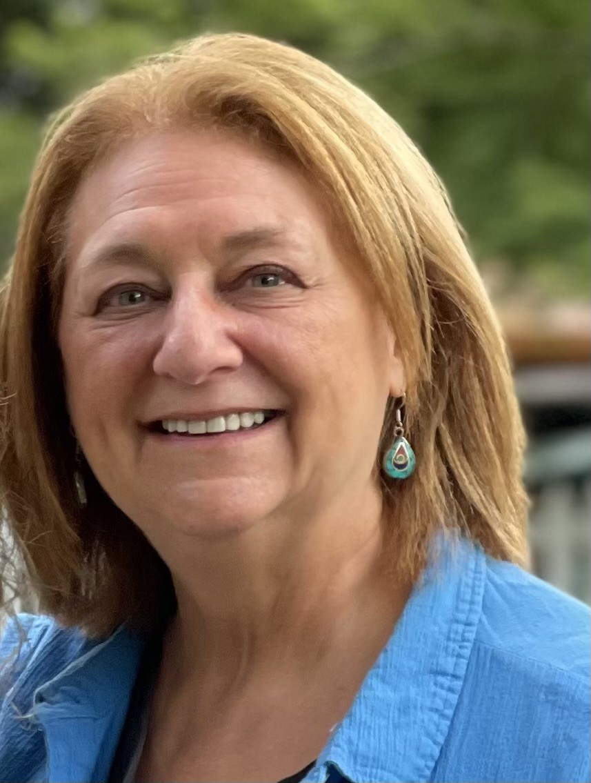 Nancy Potok wears a blue collared shirt and has shoulder-length blonde hair.